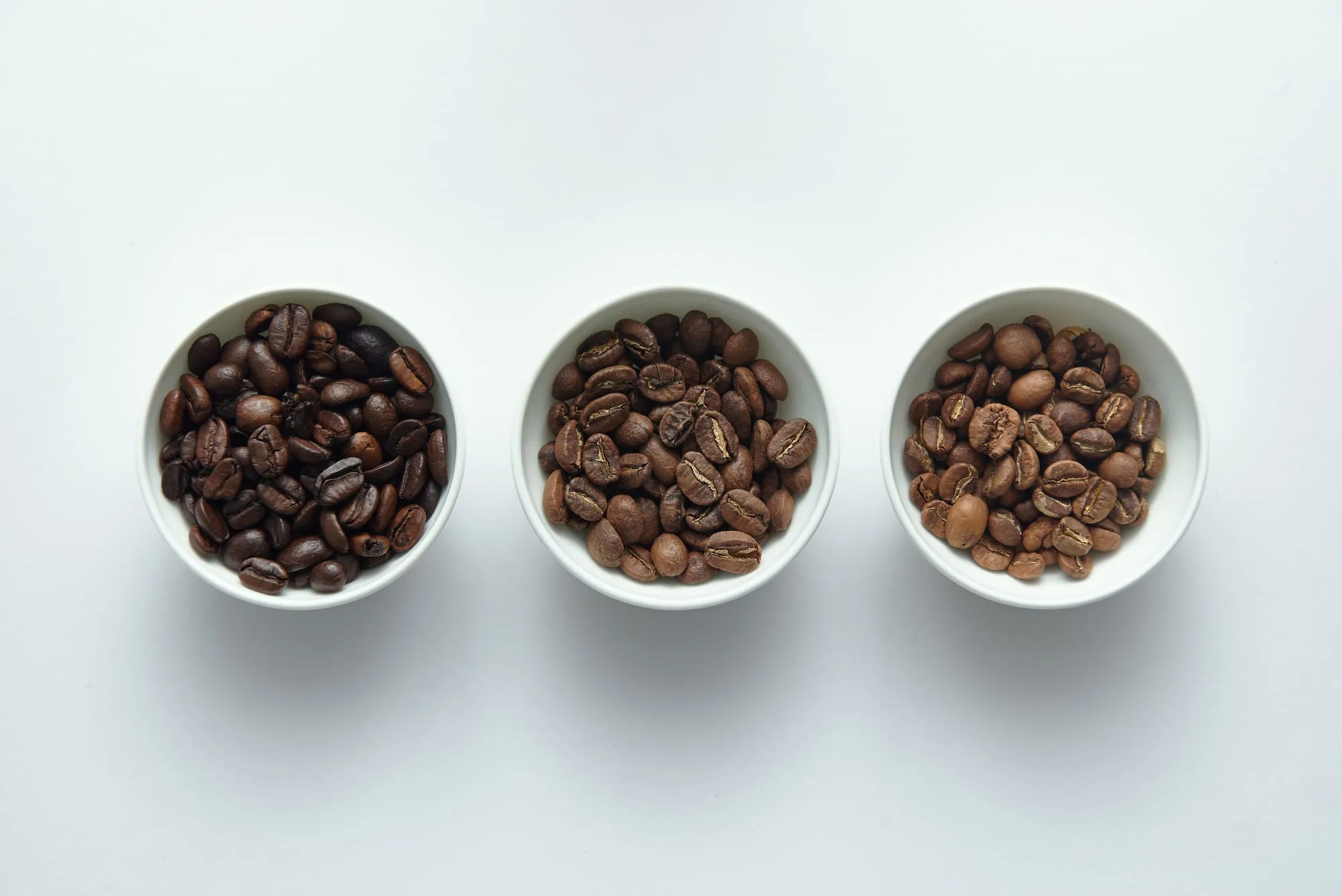 Tiga mangkuk biji kopi dengan tingkat sangrai berbeda
